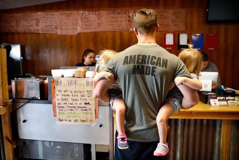 Lee Grounds of Barry, Texas, holds his twin 2-year-old daughters Leighton (left) and...