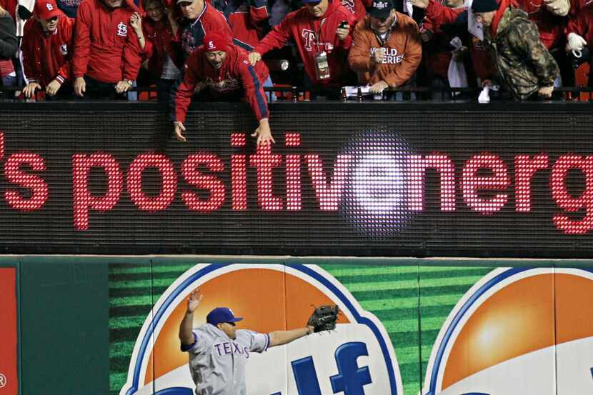St. Louis Cardinals fans reach as Texas Rangers right fielder Nelson Cruz can't come up with...