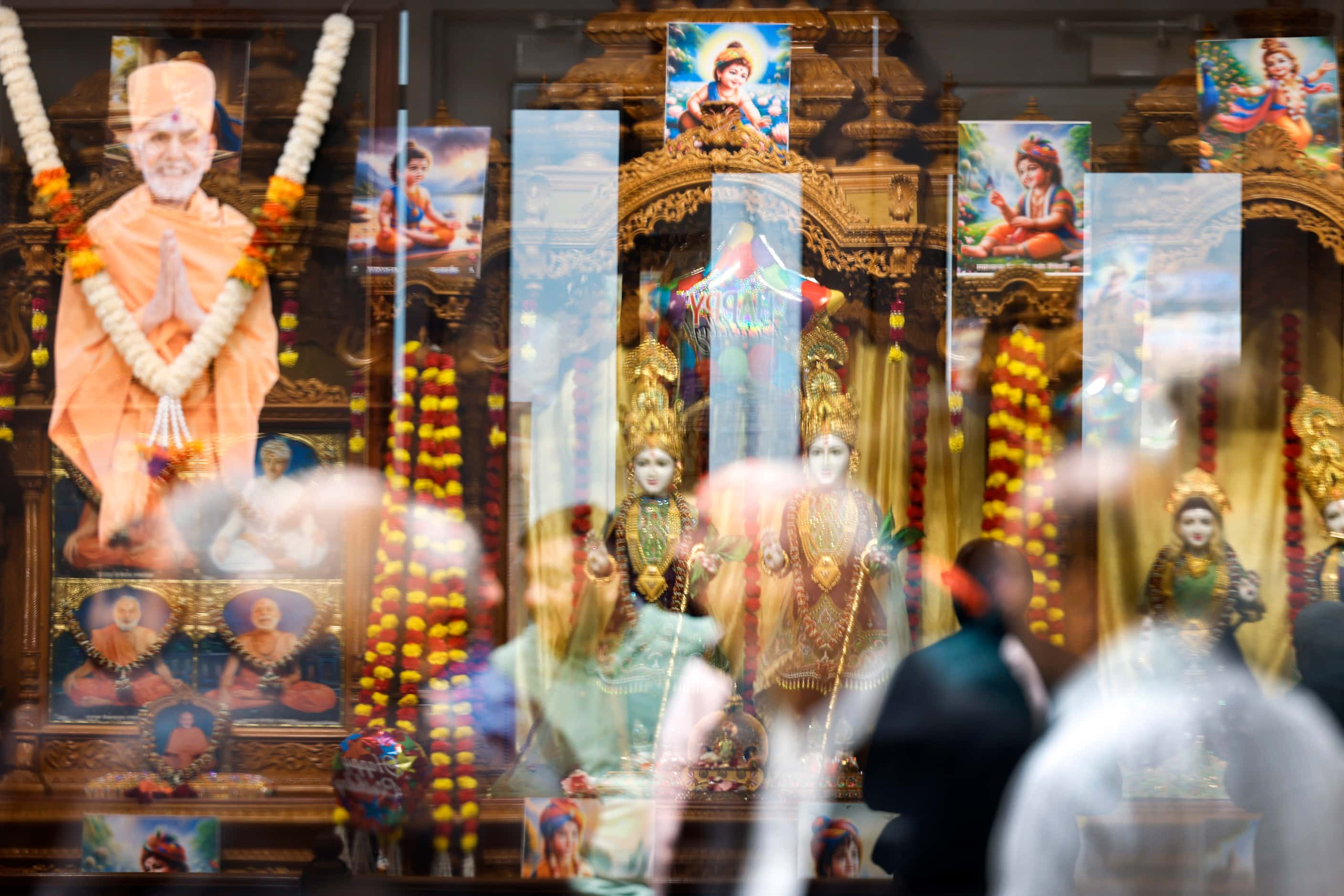 A photo of spiritual leader Mahant Swami Maharaj (left) is reflected on a glass as...