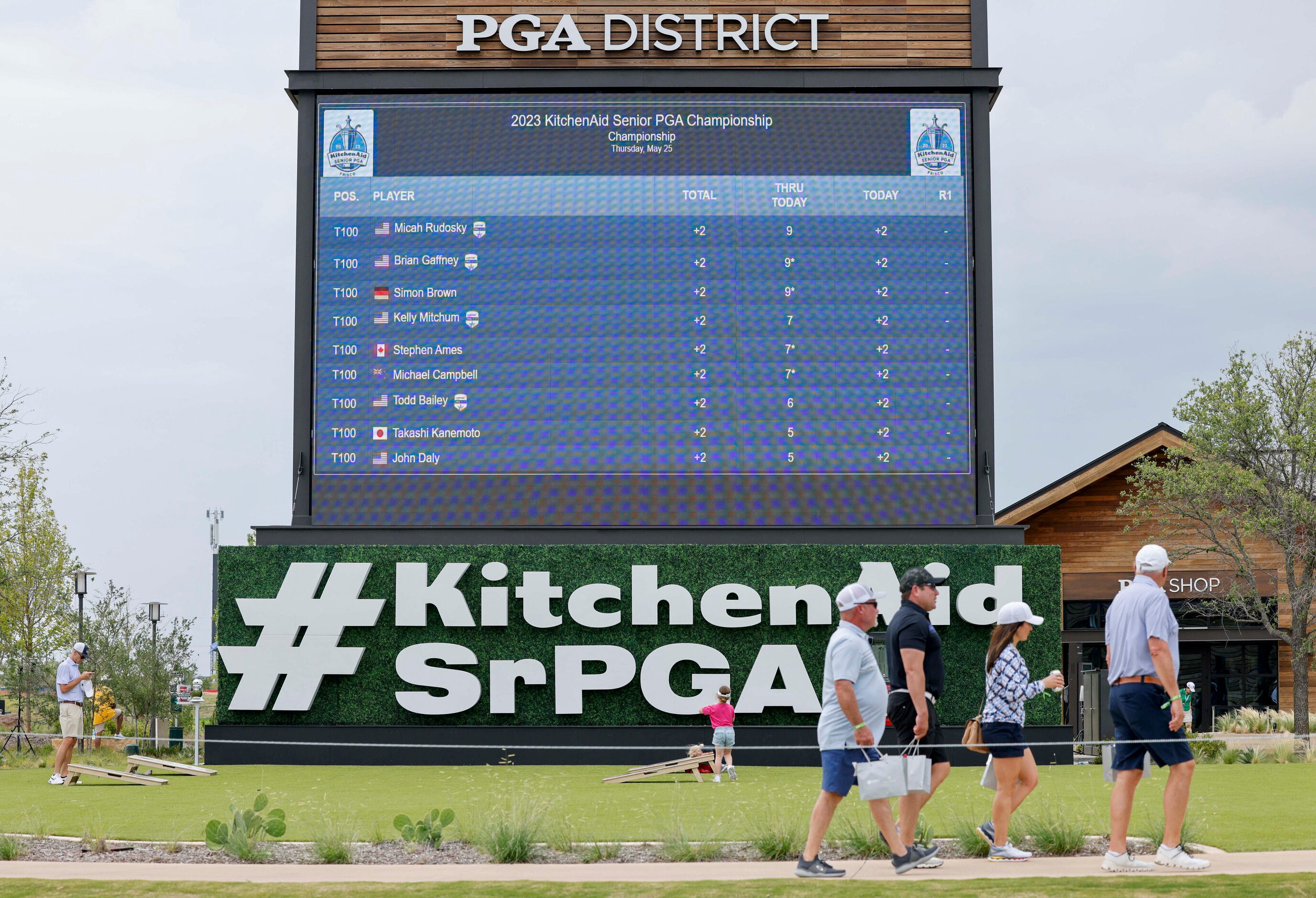 Golf fans walk past a display with the leaderboard during the first round of the 83rd...