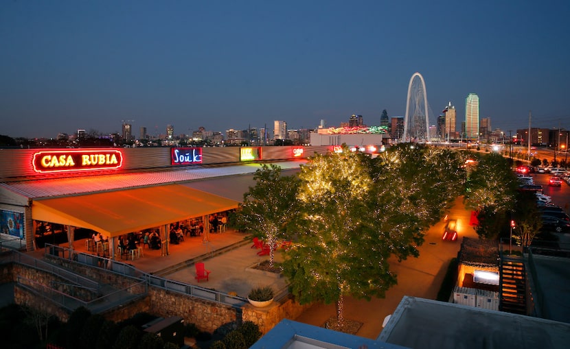 The Margaret Hunt Hill Bridge rises above the Dallas skyline and Trinity Groves restaurant...