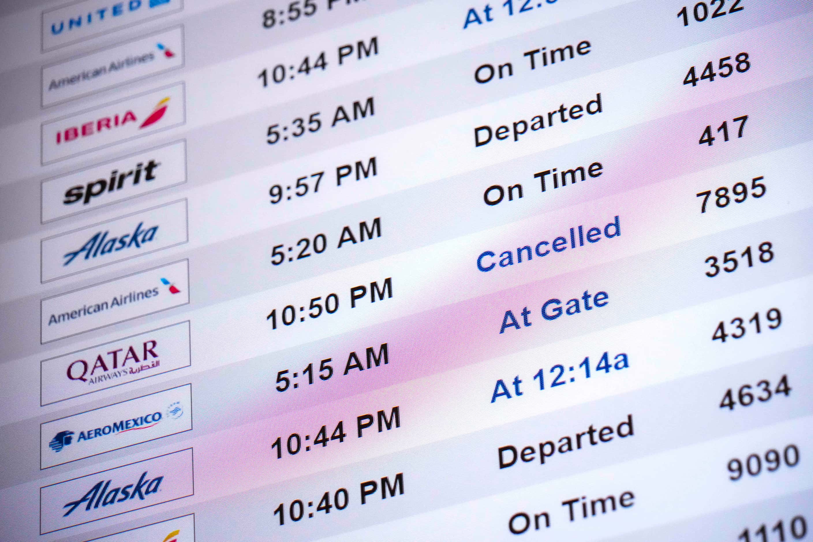 Flight status boards show a mixture of cancelled and delayed flights at DFW International...