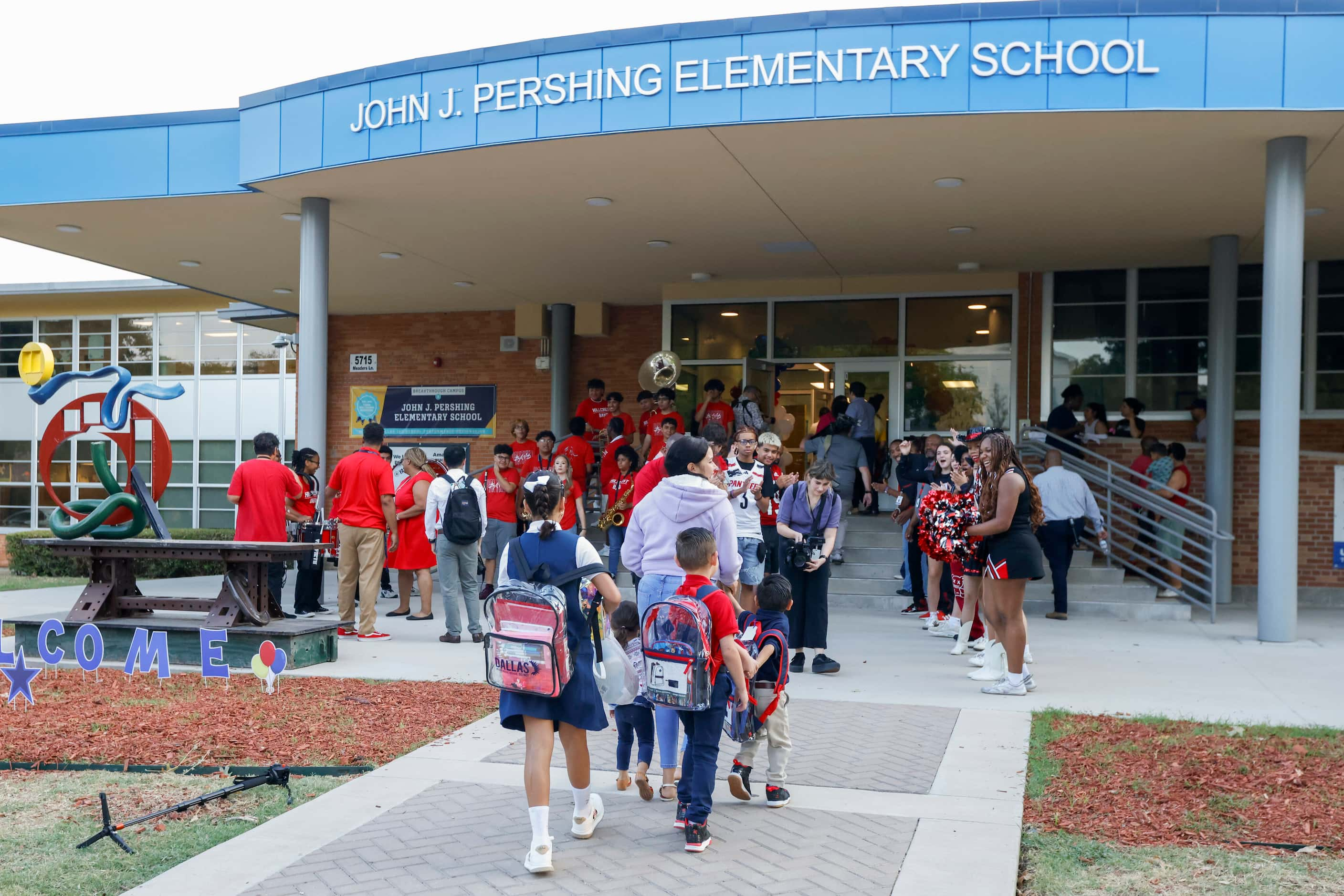 Hillcrest High School band members and student-athletes greet students at John J. Pershing...