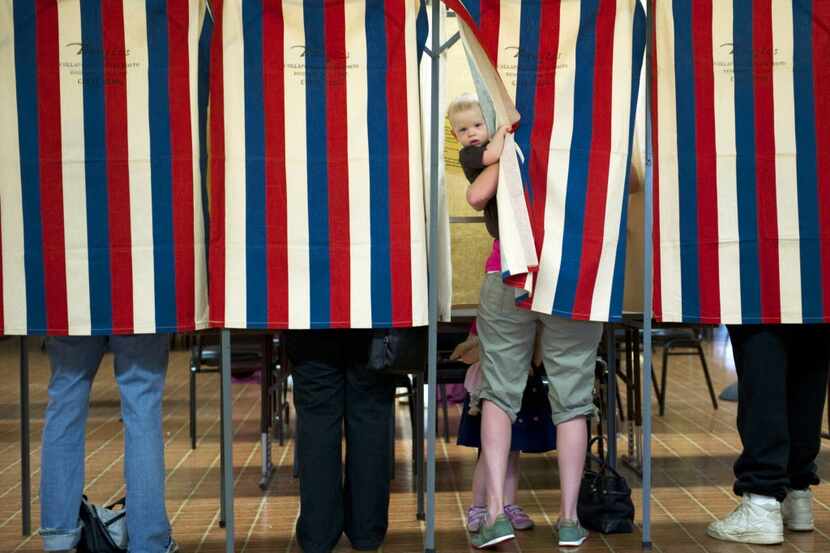 Landon Peterson peeks out of the voting booth while his mother Meghan votes March 20, 2012...