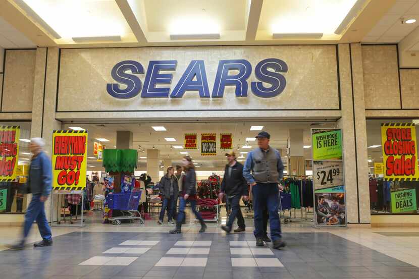 Shoppers walk by Sears department store with store closing signs at the Grand Teton Mall in...