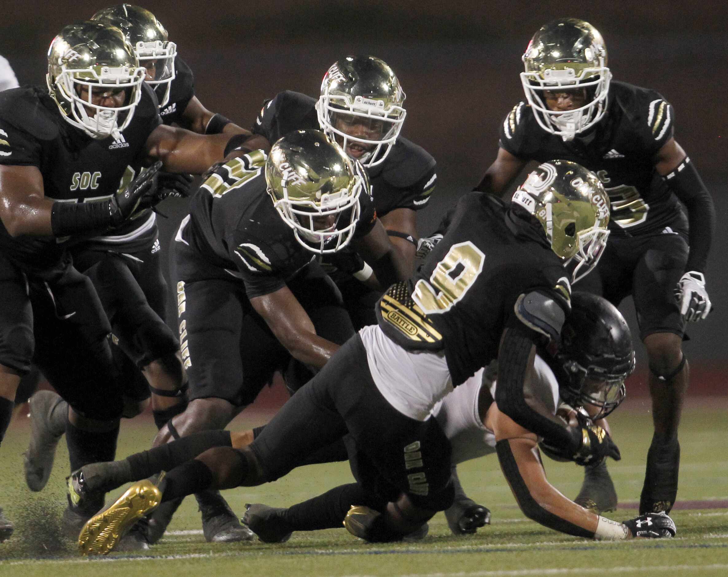 Dallas Hillcrest running back Brady Gibson (8), lower right, is swarmed by the South Oak...