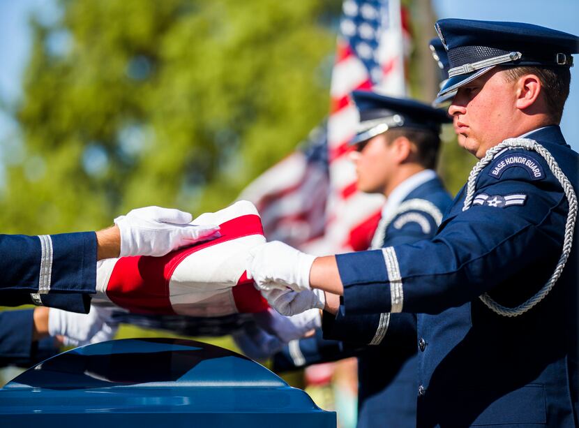 A military honor guard folds an American flag over the remains of retired Army Air Corps 1st...