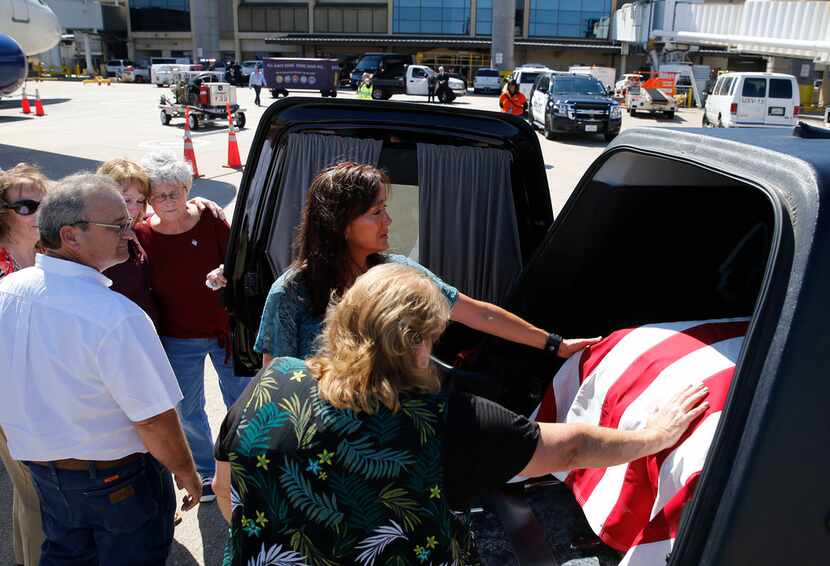 Colleen Crawford and  Christi Crawford place their hands on the coffin carrying the remains...