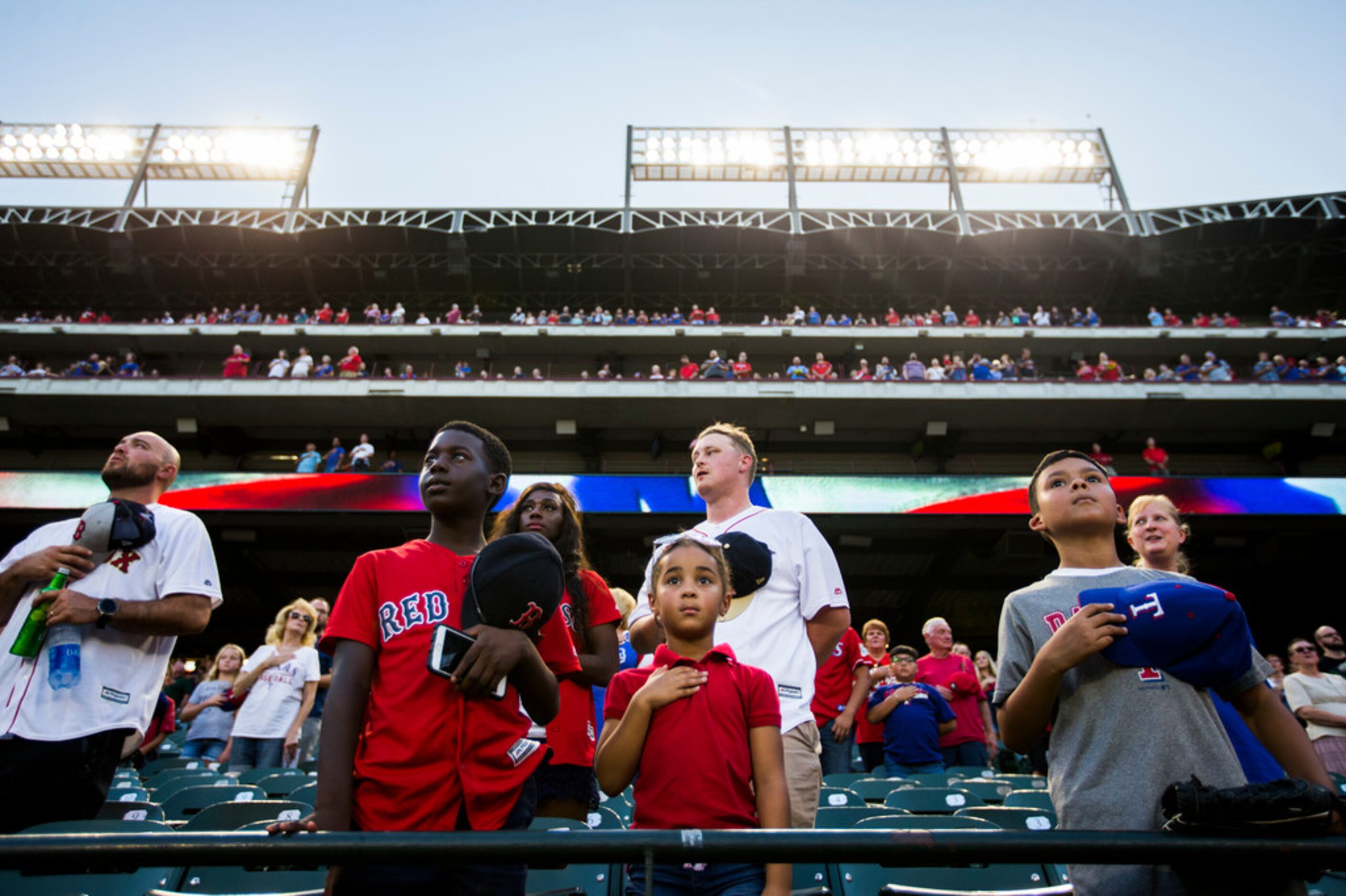 Texas Rangers fans listen to the national anthem before an MLB game between the Boston Red...