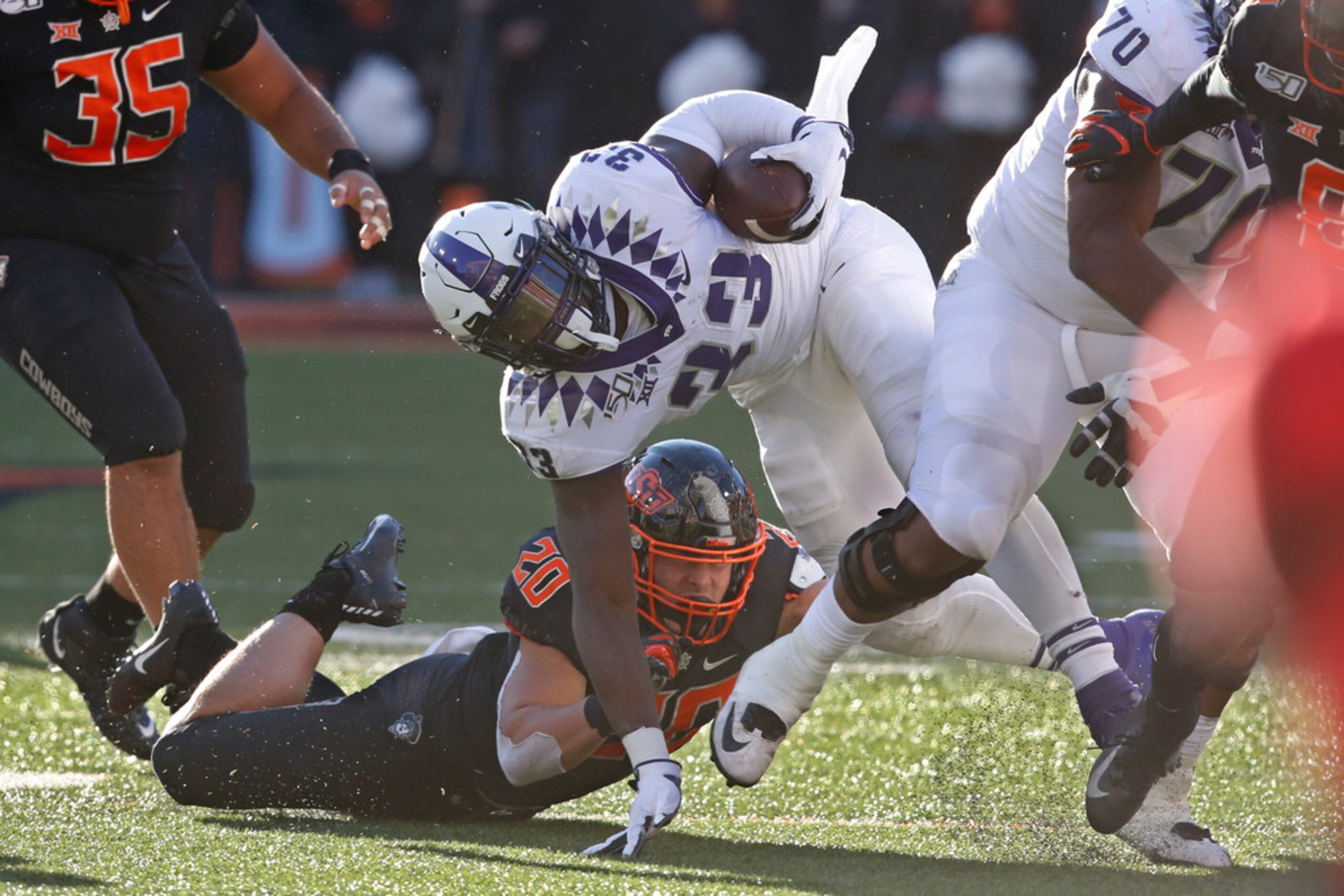 TCU running back Sewo Olonilua (33) is tackled by Oklahoma State's Malcolm Rodriguez (20) in...