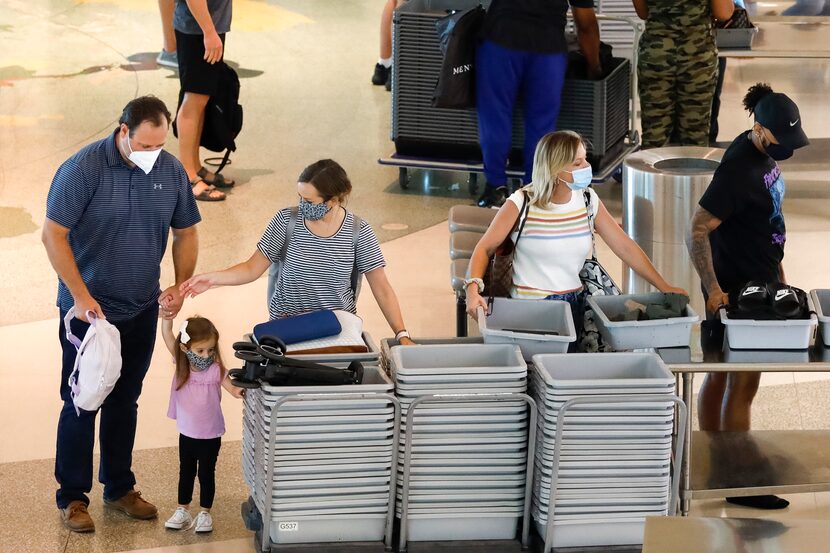 Travelers load their belongings into containers at a security checkpoint at Dallas Love...