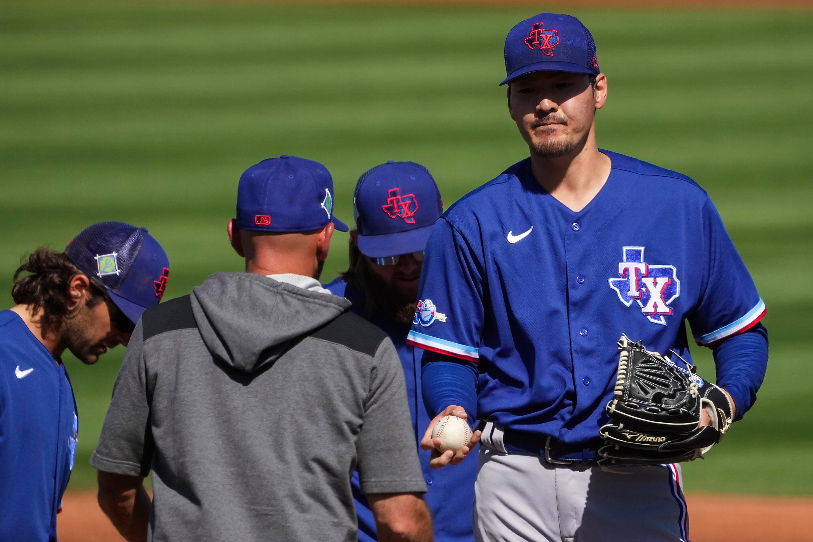 Texas Rangers pitcher Kohei Arihara hands the ball over to manager Chris Woodward as he...