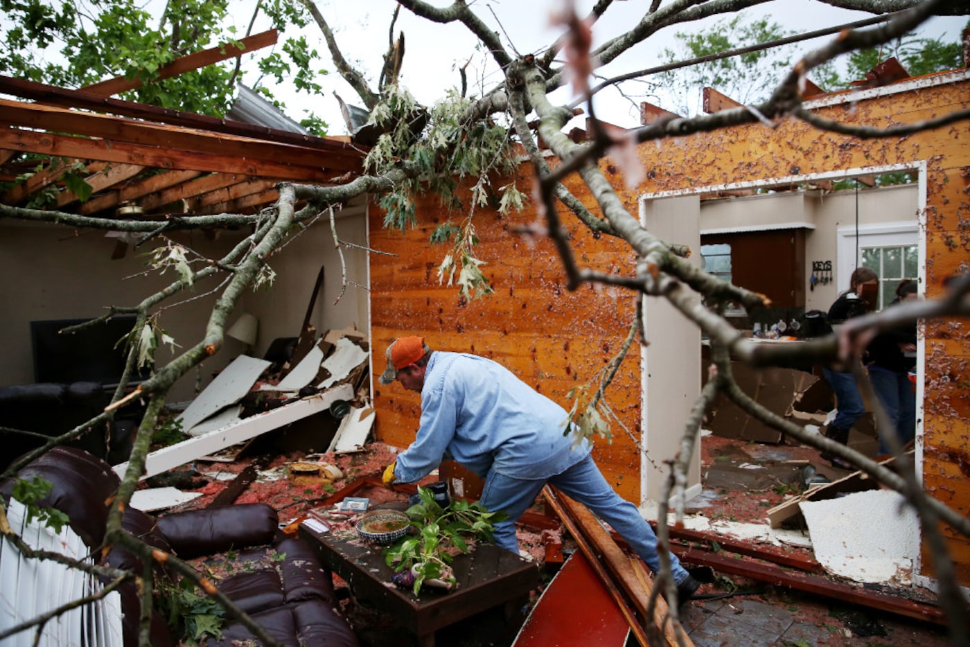 Andy Teague begins clearing debris from his living room along County Road 1910 after a...