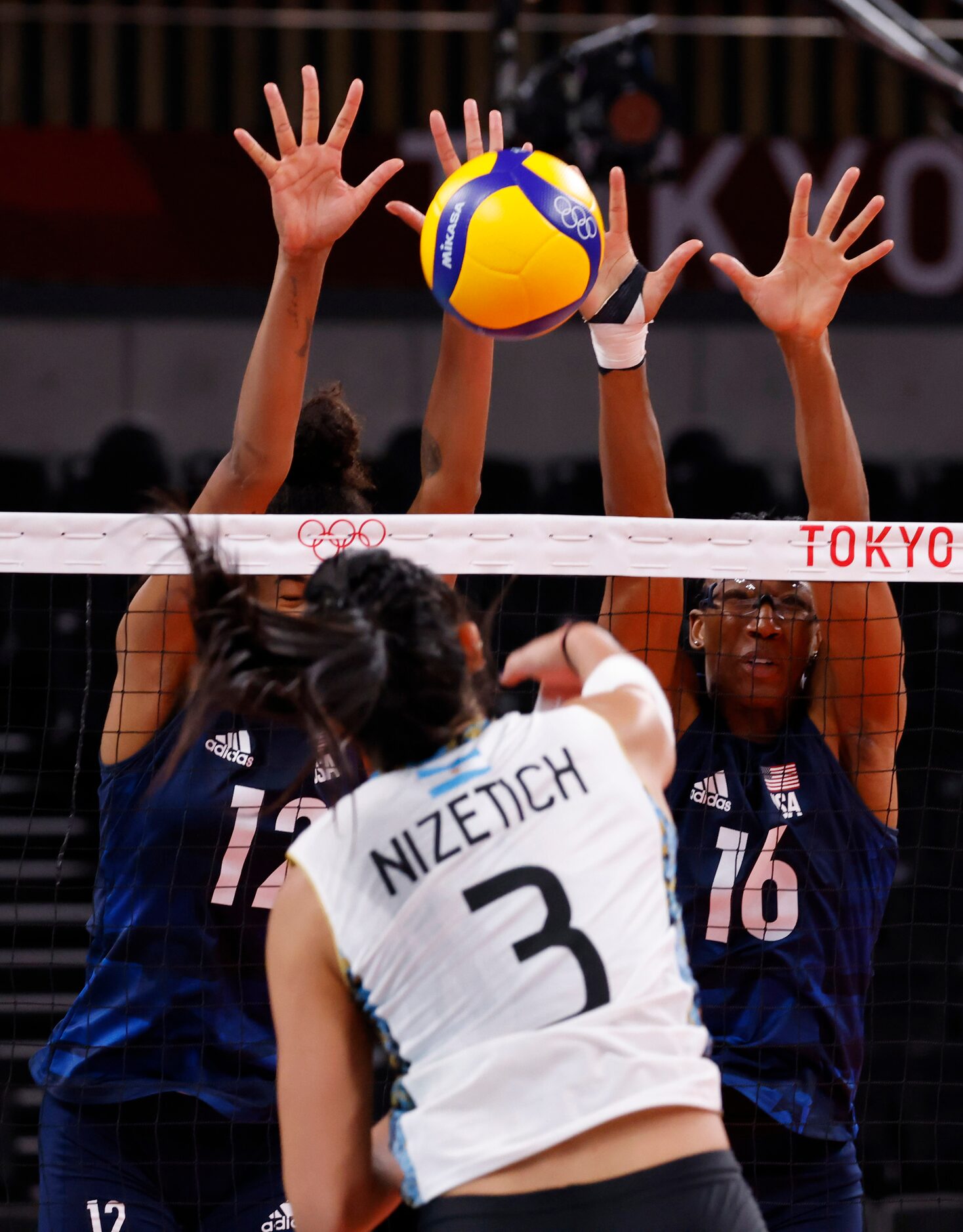 USA’s Jordan Thompson (12) and Foluke Akinradewo (16) block the ball hit by Argentina’s...