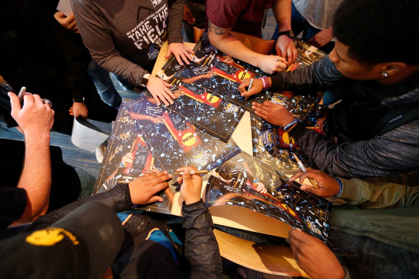 Texas A&M University-Commerce player DeionTe Haywood (top right) signs posters with...
