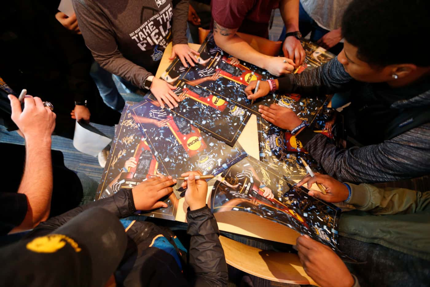 Texas A&M University-Commerce player DeionTe Haywood (top right) signs posters with...