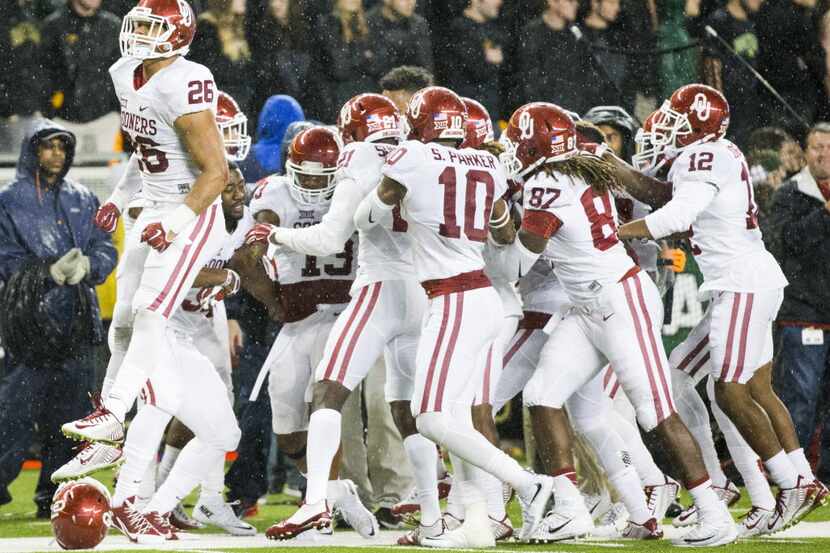 Oklahoma Sooners players celebrate an interception by safety Ahmad Thomas (13) that sealed...