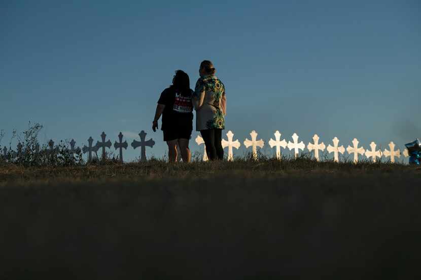 Sonia Yanez (left) and Laura Torres mourn near the 26 crosses set up for the victims killed...