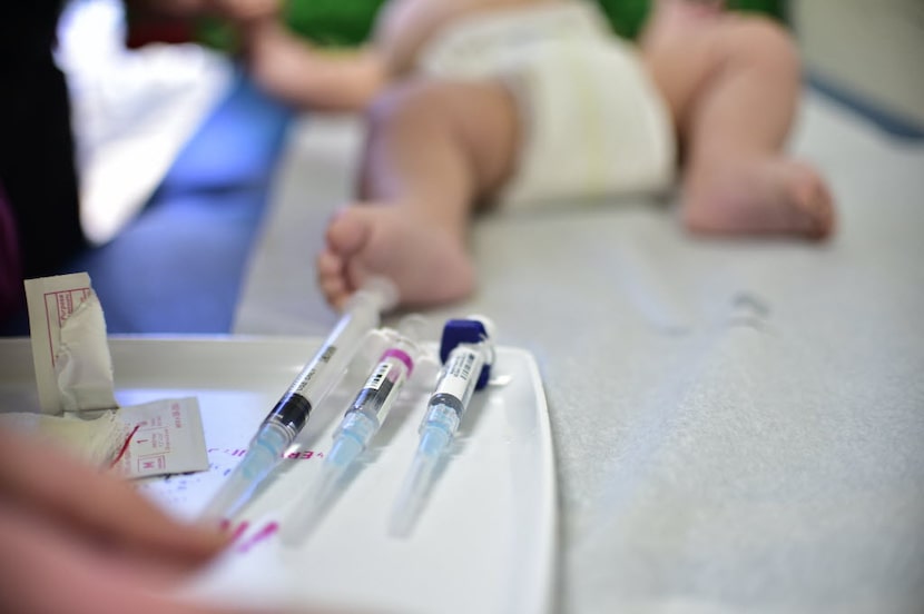 Nurse Robyn Kerner reaches for a syringe to give immunizations to Mason Moores at Pecan...