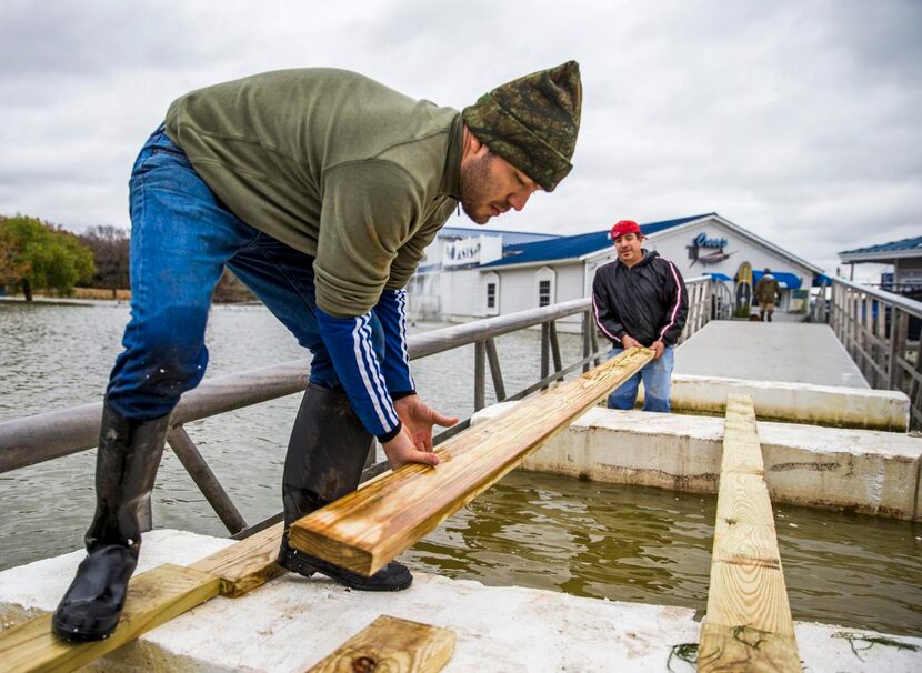 
David Torres (left) and Flavio Ruiz prepare a temporary walkway across the flooded parking...