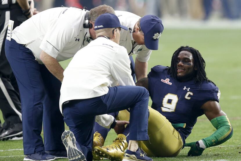 FILE - In this Jan. 1, 2016, file photo, Notre Dame linebacker Jaylon Smith (9) is attended...