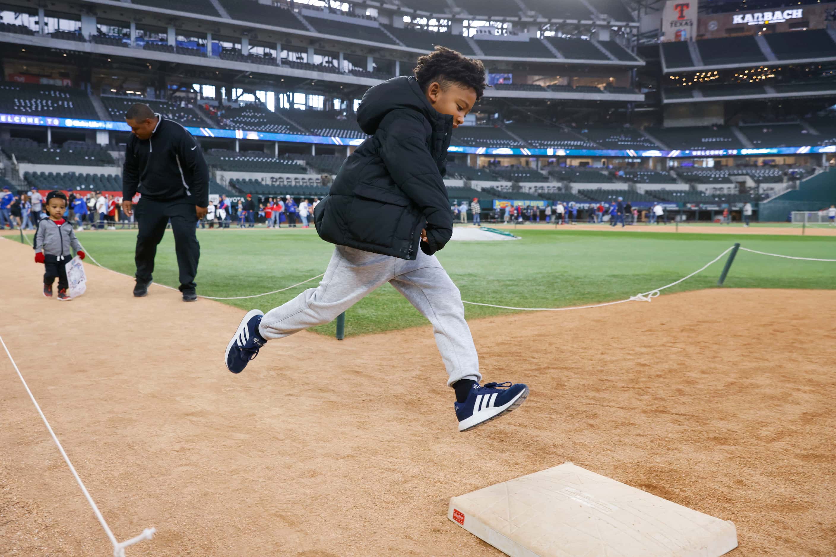 Braxton Ellis, 7, leaps to the first base as he runs the bases during Texas Rangers Fan Fest...