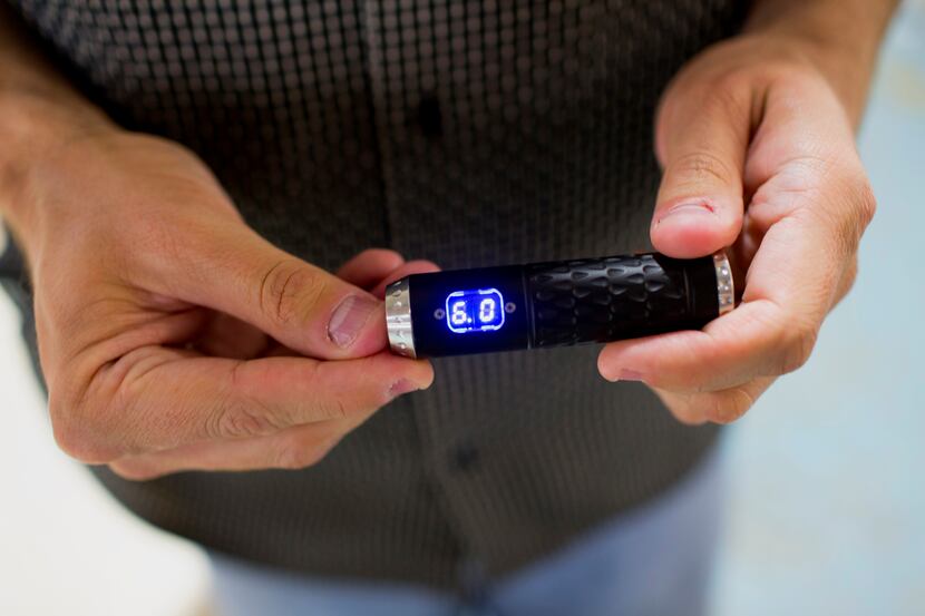 An employee displays a model electronic cigarette for a photograph at the ProVape Inc....