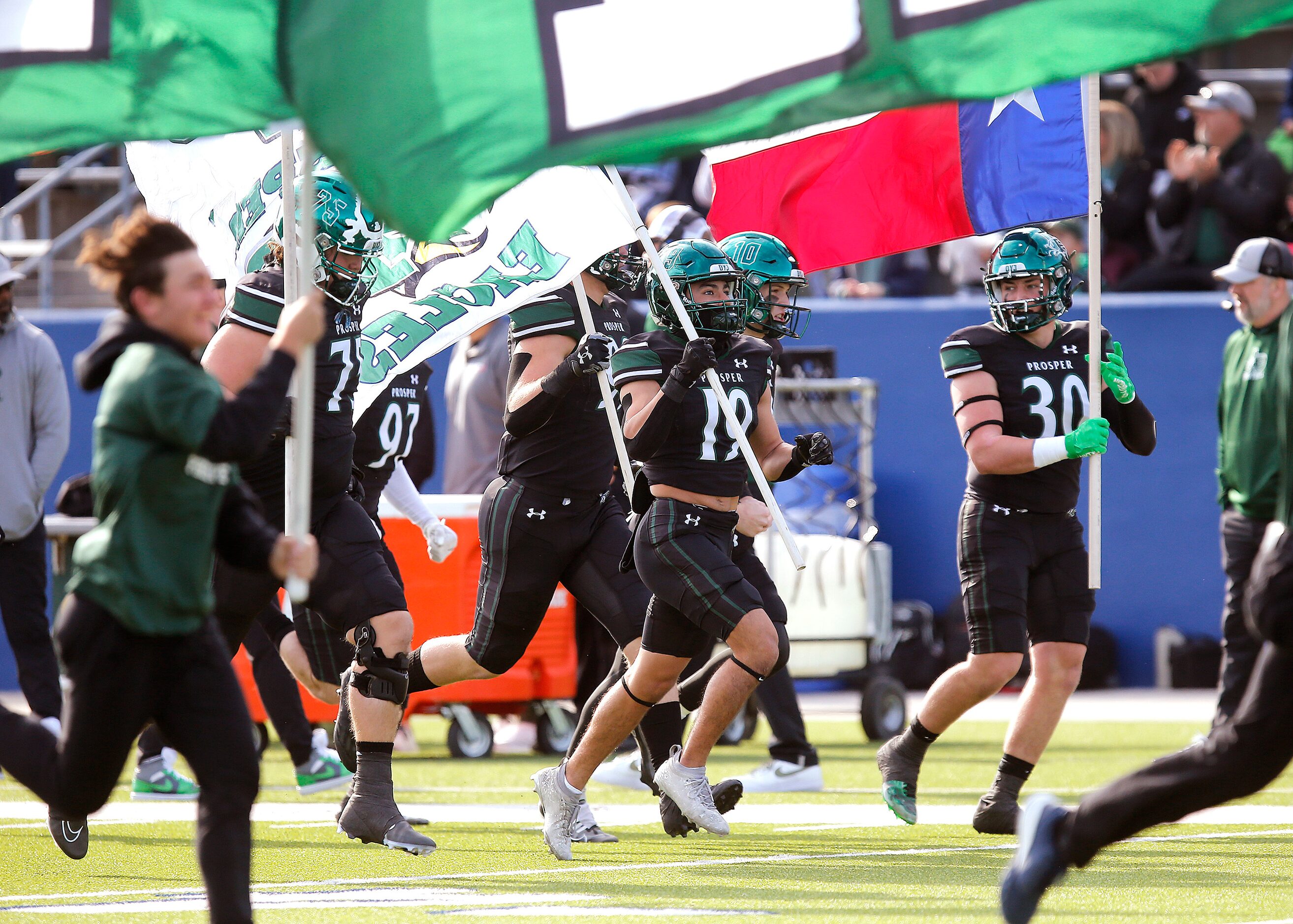 Prosper High School’s Bo Mongaras (19) carries a flag onto the field before kickoff as...