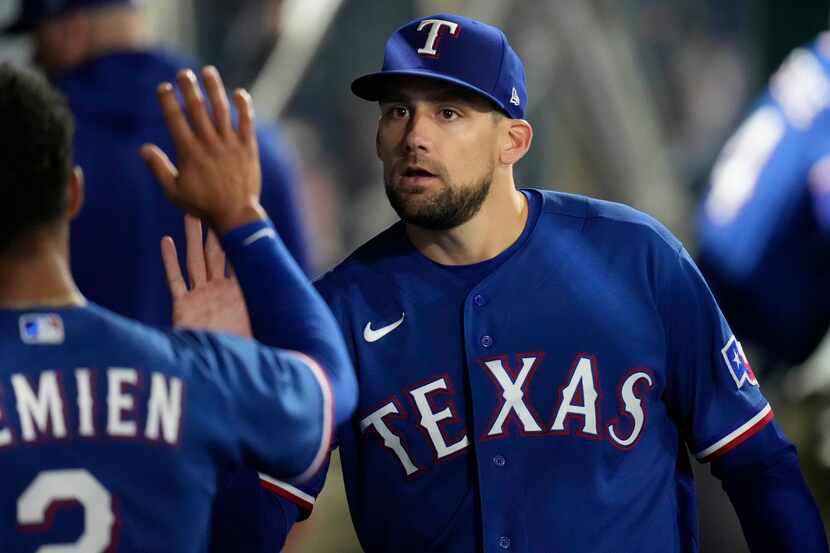 Texas Rangers starting pitcher Nathan Eovaldi, right, high-fives Marcus Semien in the dugout...