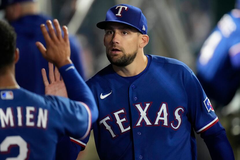 Texas Rangers starting pitcher Nathan Eovaldi, right, high-fives Marcus Semien in the dugout...