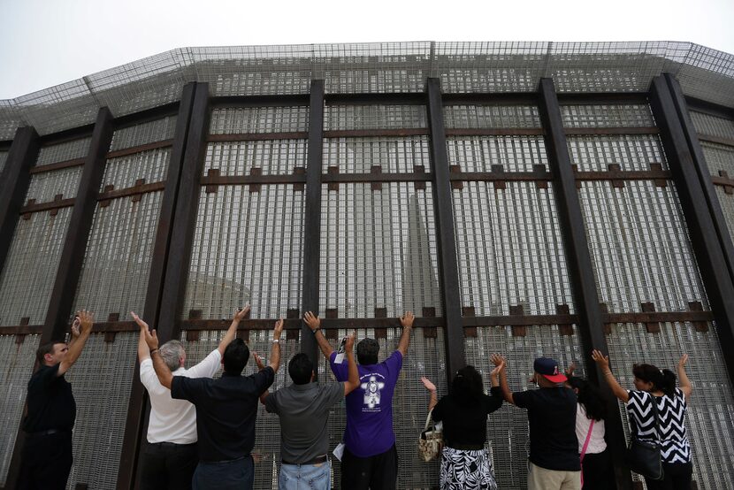 In this July 14, 2013, photo, pastors and others raise their arms on the San Diego side of a...