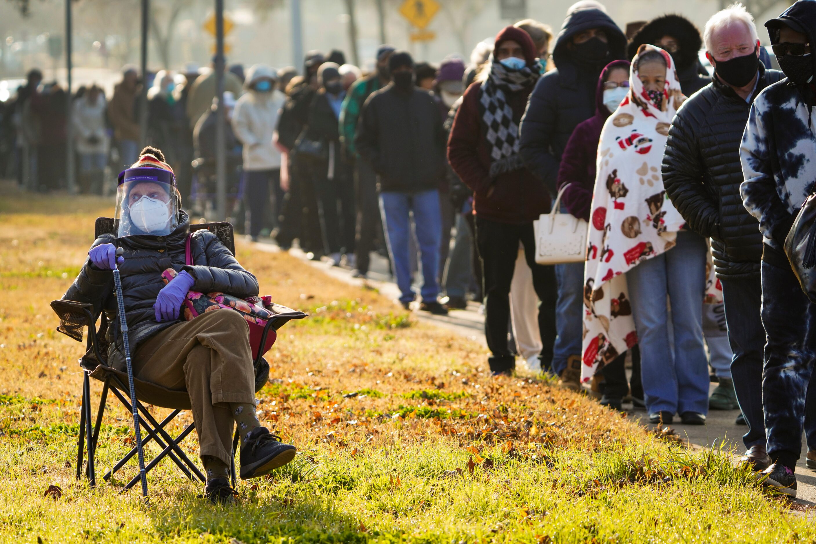 Florence Mullins, 89, sits in a chair as a family member holds her place in a long line to...