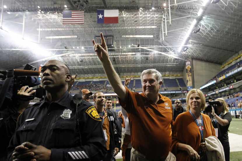 Texas Longhorns head coach Mack Brown shows the hook 'em horns sign as he exits the field...