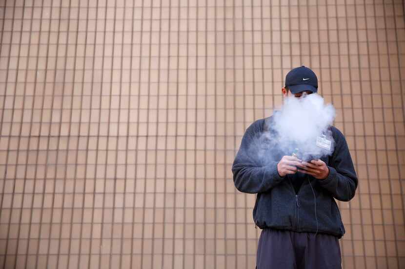 Tommy Nguyen, 27, vapes outside El Centro College in downtown Dallas. Texas legislators may...