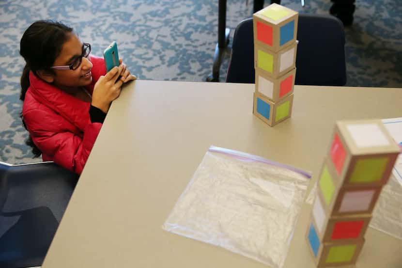 
Ariva Bhatt, 13, of Plano takes a photograph of a solved Instant Insanity puzzle at the...
