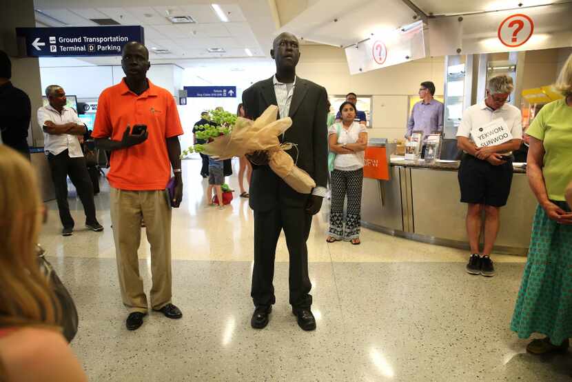 Abraham But (center) waits at the international arrivals gate with cousin Philip Machok for...