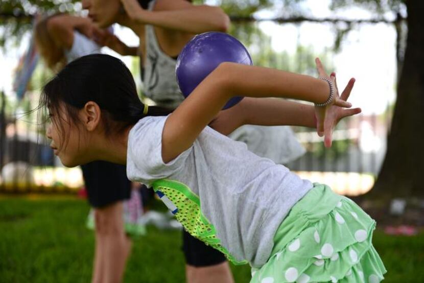 
Vika Yun, 8, rolls a ball down her back during summer camp at River of Life.
