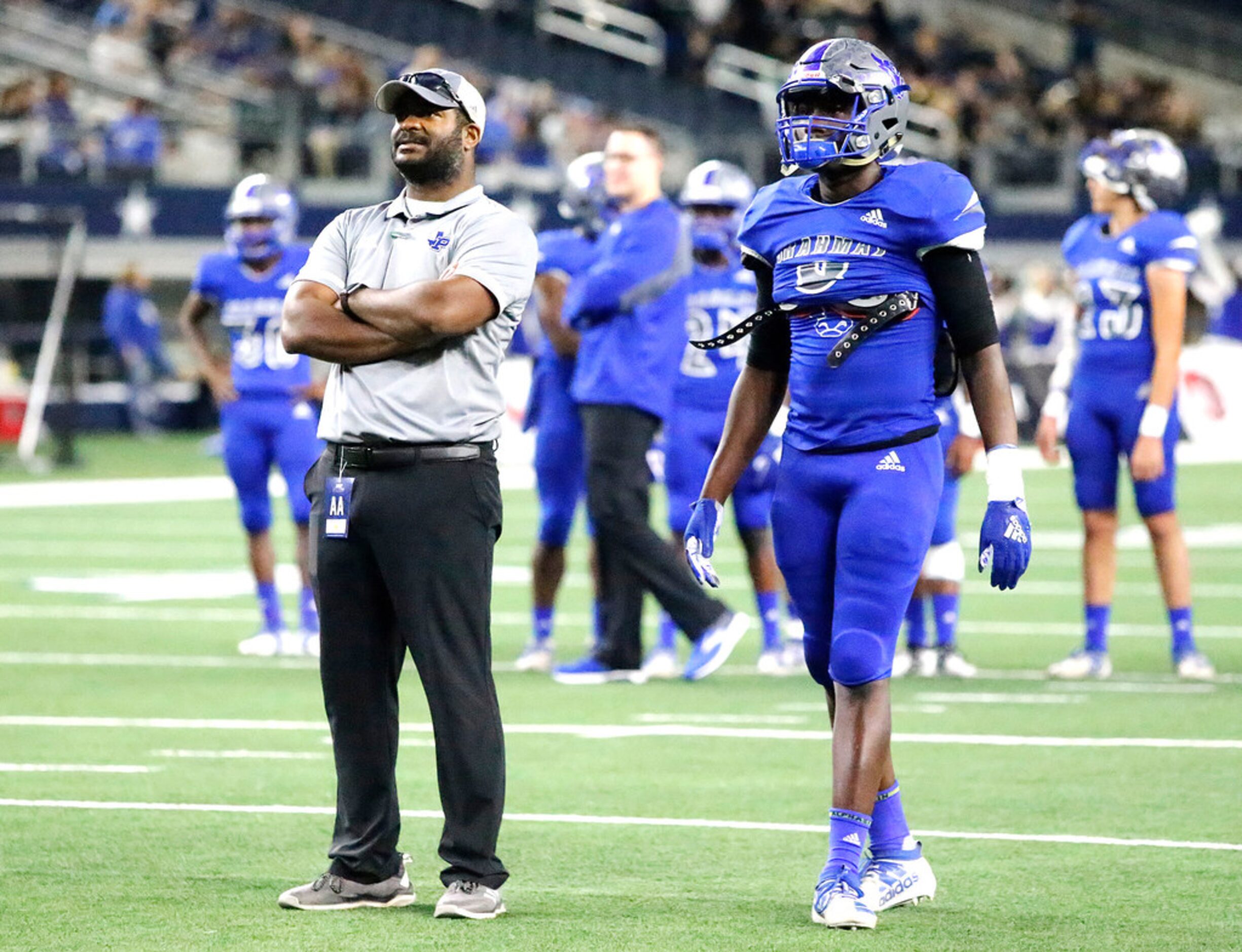 Omaha Pewitt High School head coach Triston Abron watches his team warm up before kickoff as...