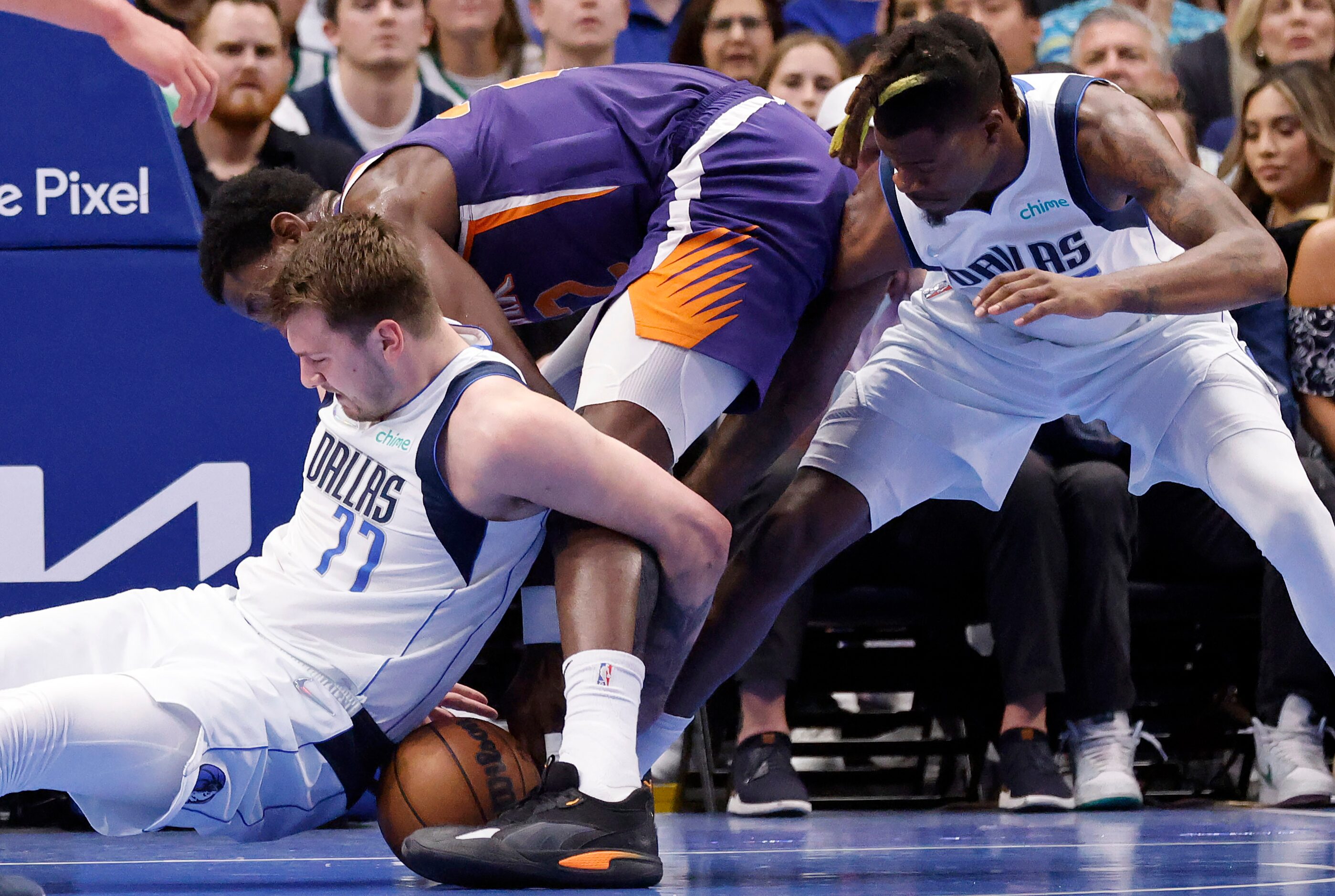 Dallas Mavericks guard Luka Doncic (77) battles for a loose ball with Phoenix Suns center...