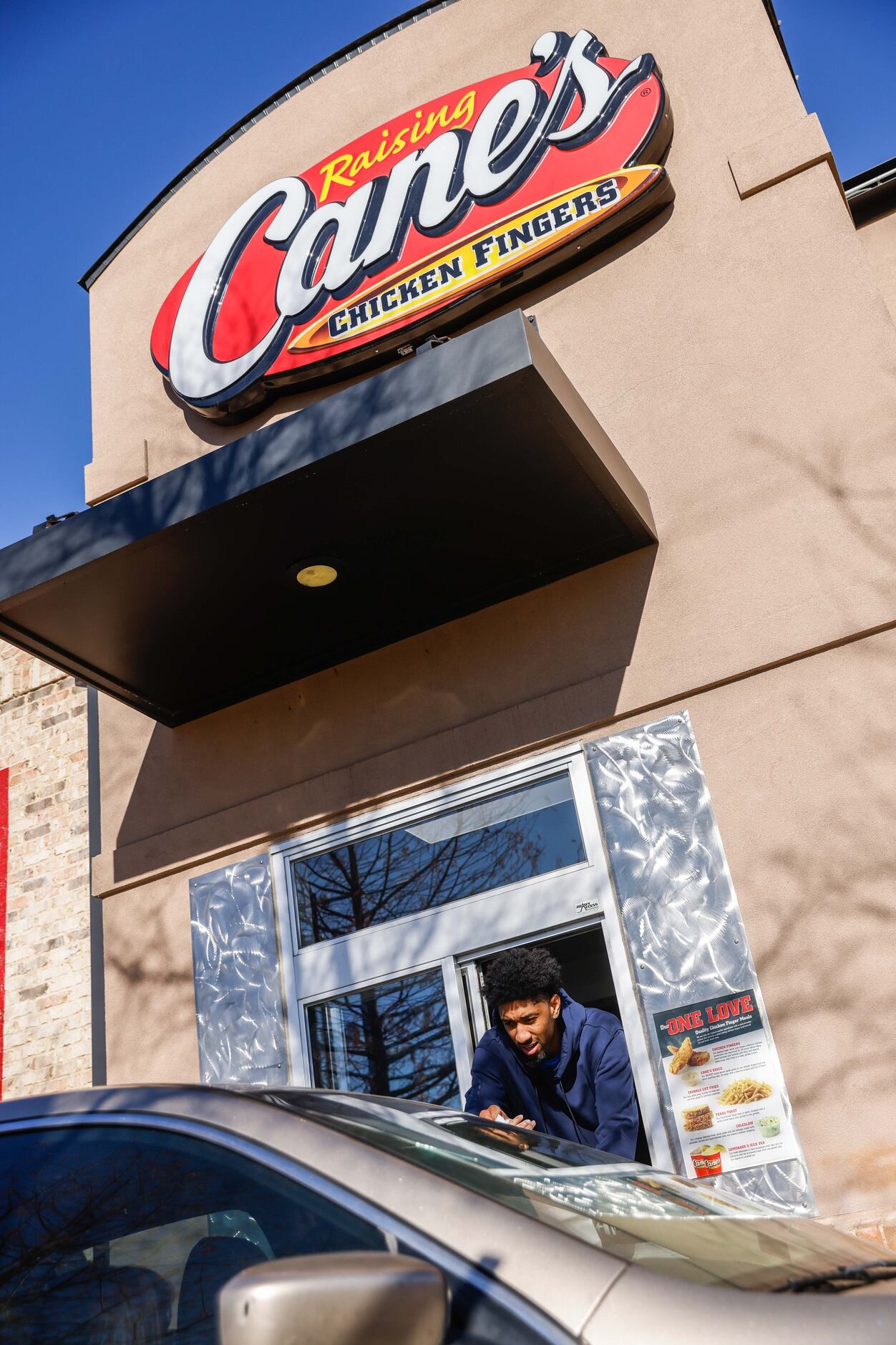 Mavericks player Christian Wood serves lunch at the Raising Cane’s in Dallas on Wednesday,...