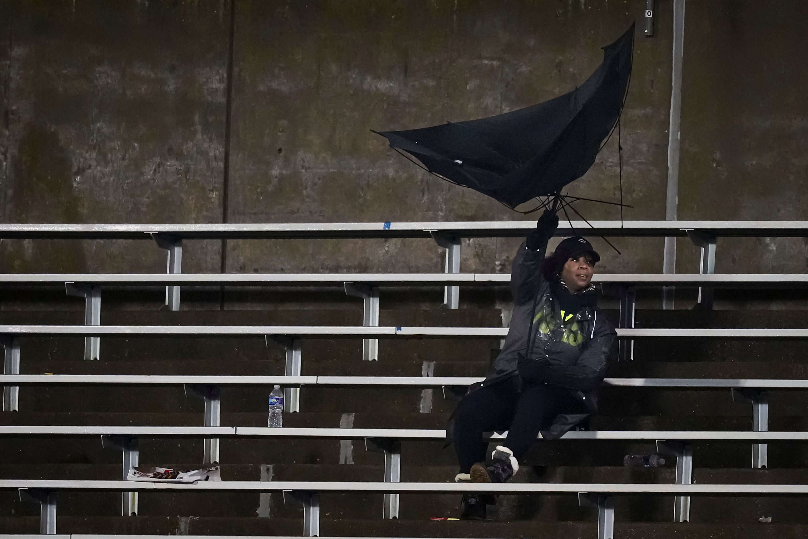 A fan struggles with an umbrella in the wind during the second half of a District 11-6A high...