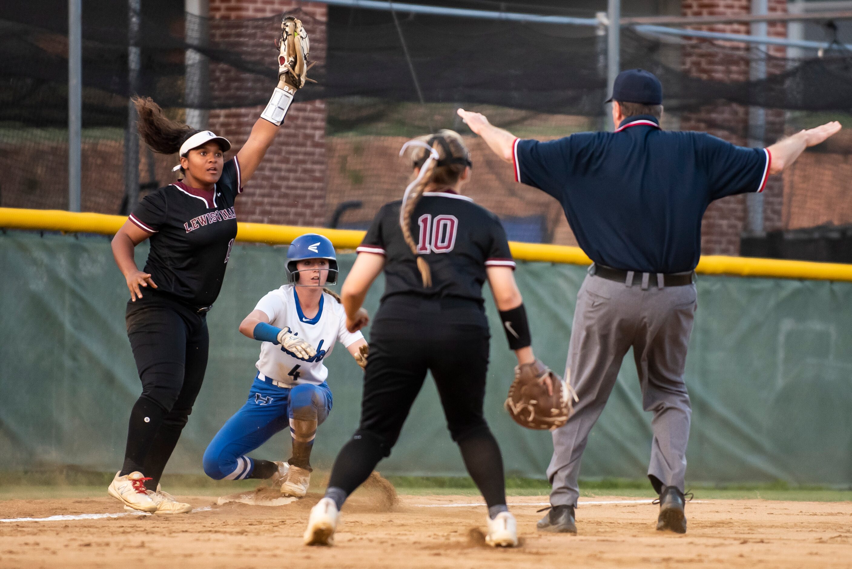 Lewisville’s Lizzie Smith (19) raises her glove after making an attempt to tag out Hebron’s...