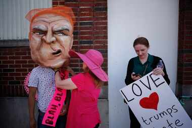 Leslie Harris (center) helps Alex Garcia put on a Donald Trump head as Maryellen Oltman...