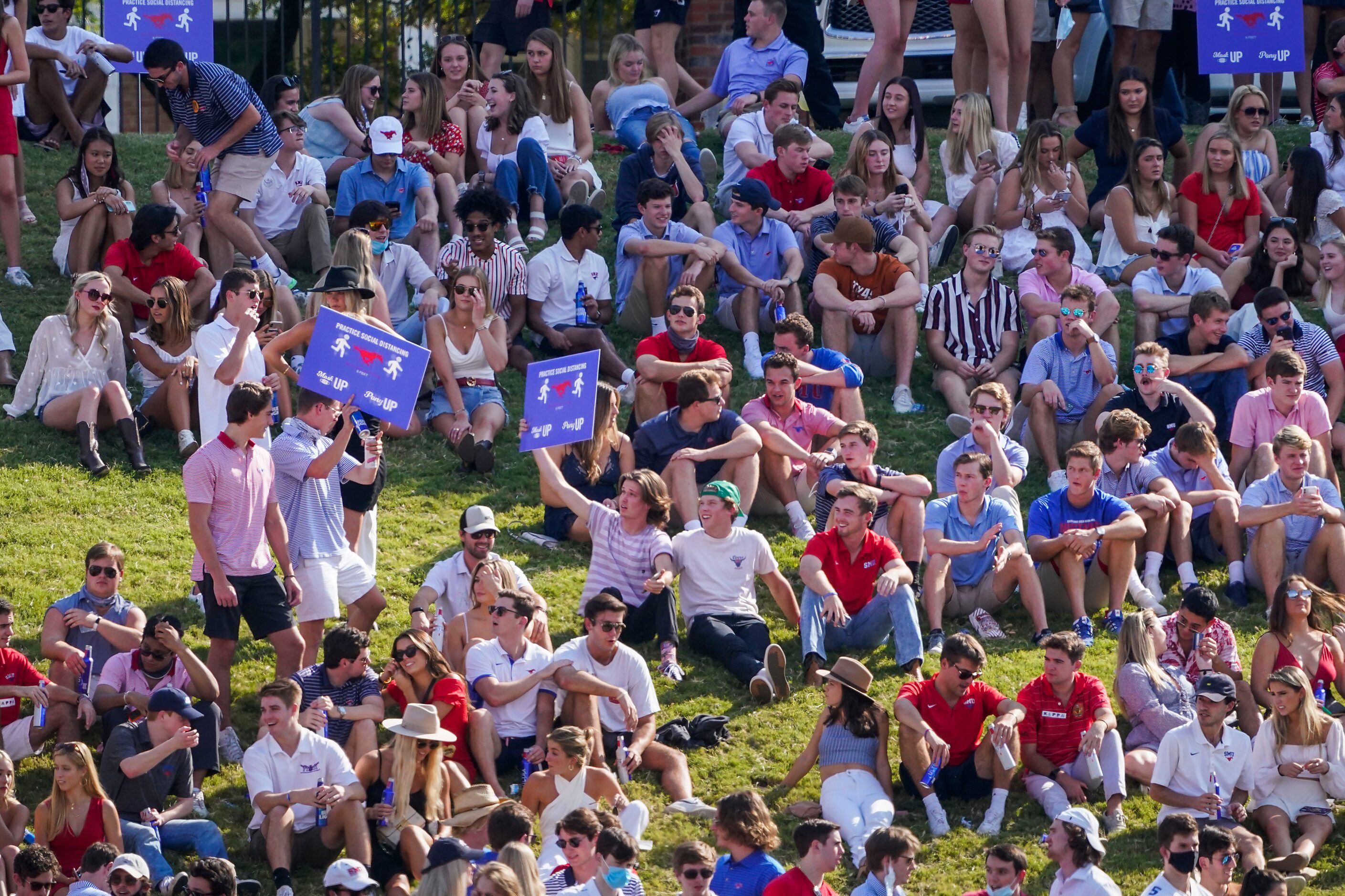 SMU students on the hill hold social distancing signs that had been pulled up from the grass...