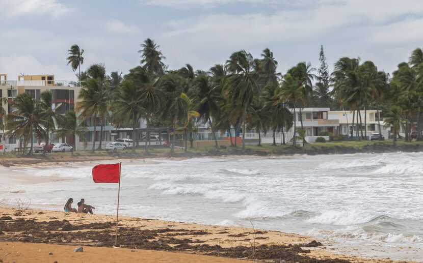 Turistas sentados en la playa La Pared mientras la tormenta tropical Ernesto pasa por...