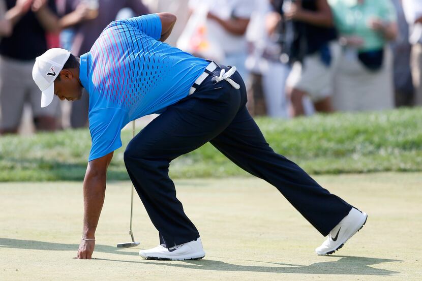 FARMINGDALE, NY - AUGUST 24:  Tiger Woods takes his ball out of the hole on the ninth green...