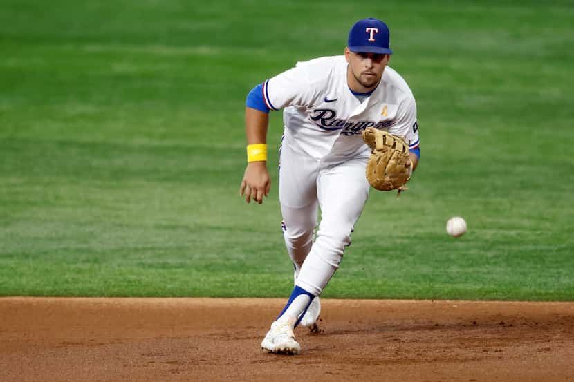 Texas Rangers first baseman Nathaniel Lowe (30) fields a grounder by Colorado Rockies batter...