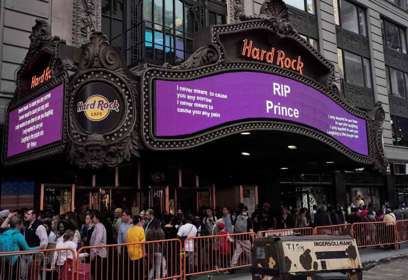 People walk past a "Rest In Peace" message for singer Prince, on an electronic board at the...
