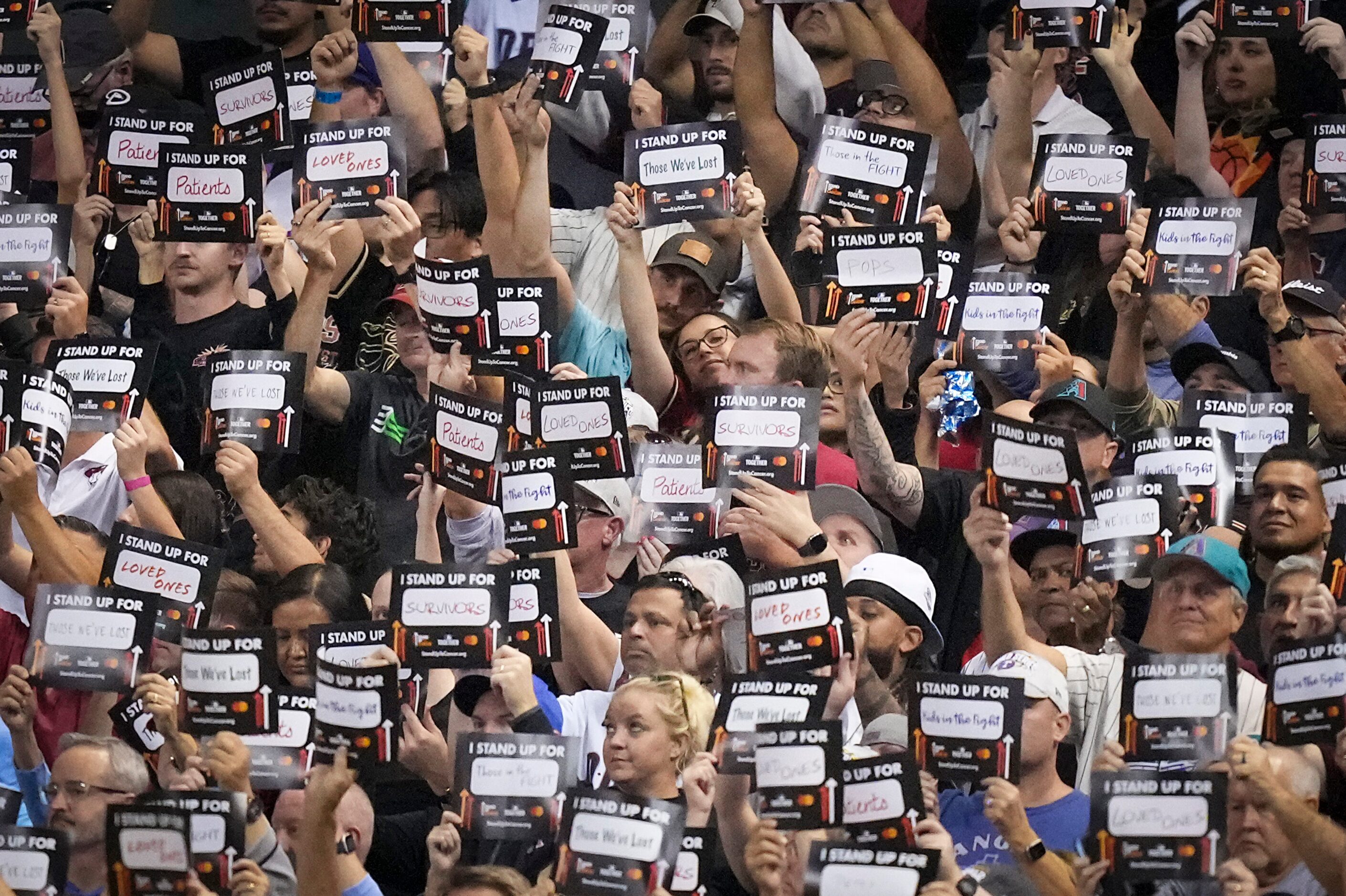 Fans hold up Stand Up to Cancer signs after the fifth inning in Game 4 of the World Series...