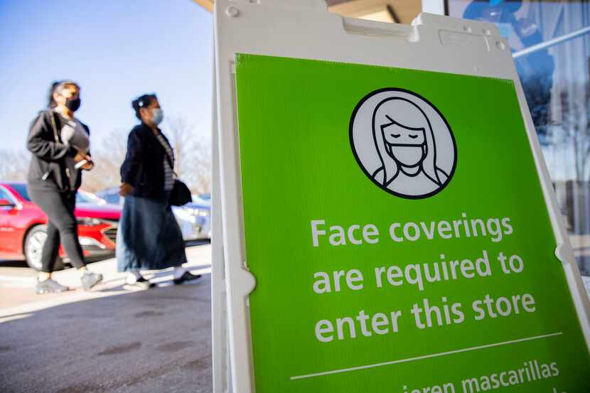 Shoppers pass by a face mask sign at the Ross in City Place in Dallas on Tuesday. Gov. Greg...
